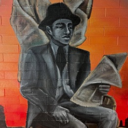 a mural on a wall of a man reading a newspaper