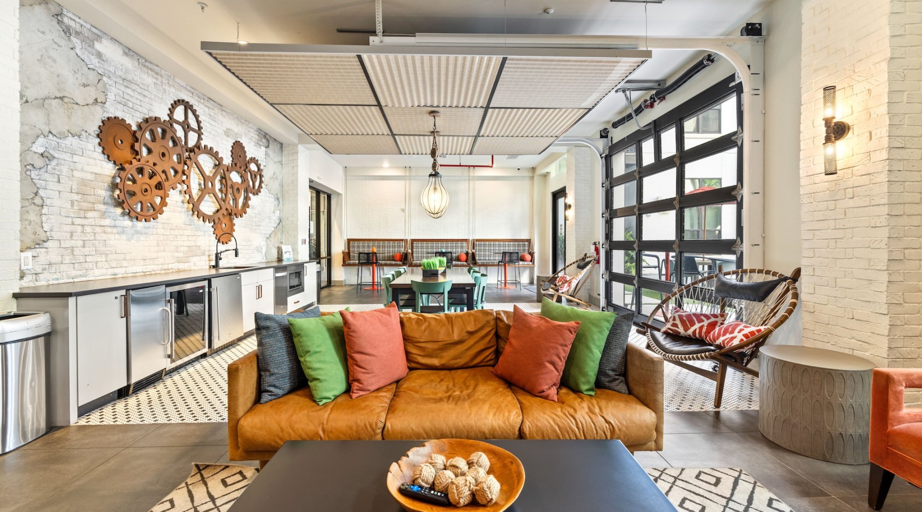 a spacious well-lit lounge with a leather sofa and a kitchen